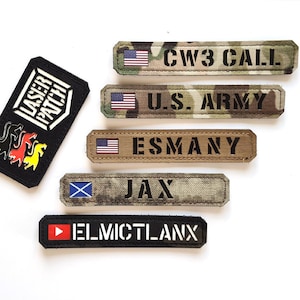 Pode incluir: Cinco patches bordados diferentes com vários designs e textos. Os patches são todos retangulares e têm uma borda preta. O patch superior tem uma bandeira americana vermelha, branca e azul e o texto "CW3 CALL". O segundo patch tem uma bandeira americana vermelha, branca e azul e o texto "U.S. ARMY". O terceiro patch tem uma bandeira americana vermelha, branca e azul e o texto "ESMANY". O quarto patch tem uma bandeira escocesa azul e branca e o texto "JAX". O patch inferior tem um botão de reprodução vermelho e o texto "ELMICTLANX".