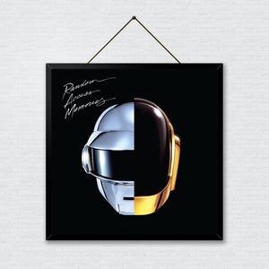 May include: Framed album art featuring a split-face helmet design. One side is silver, the other is black and gold. The album title "Random Access Memories" is written in cursive at the top. The background is black.