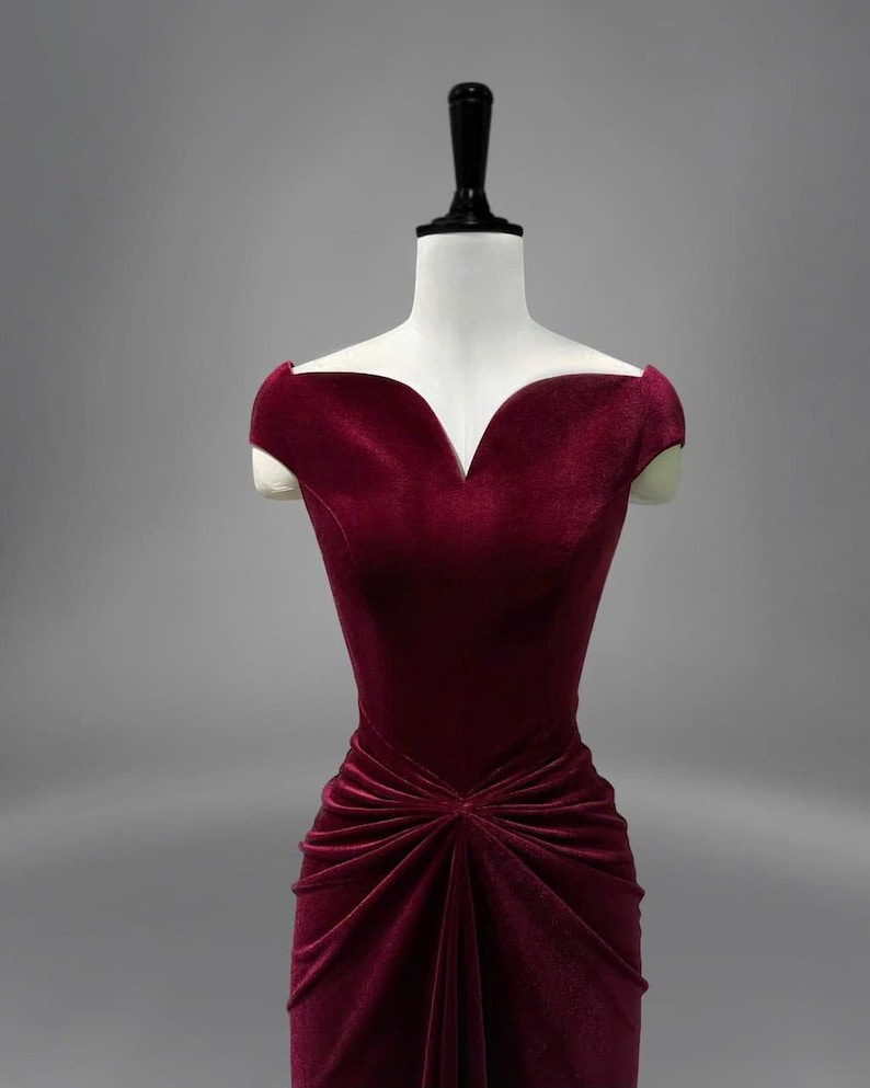 May include: A burgundy velvet dress with a sweetheart neckline and a fitted bodice. The dress has a gathered skirt and short cap sleeves.
