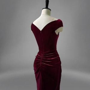 May include: A burgundy velvet dress with a V-neckline and short sleeves. The dress has a fitted bodice and a flowing skirt.