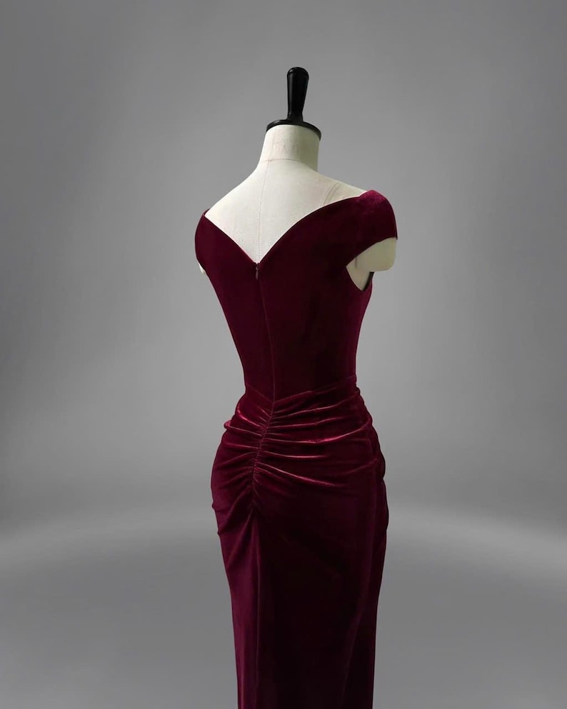 May include: A burgundy velvet dress with a V-neckline and short sleeves. The dress has a fitted bodice and a flowing skirt.
