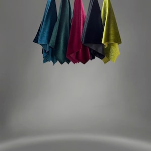 May include: Six fabric swatches hanging from strings against a gray background. The swatches are teal, green, burgundy, black, and yellow.