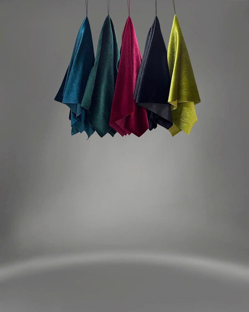 May include: Six fabric swatches hanging from strings against a gray background. The swatches are teal, green, burgundy, black, and yellow.
