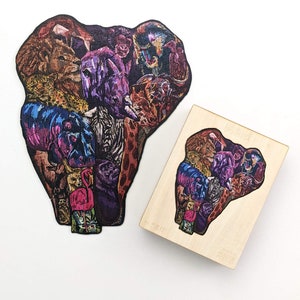 Puede incluir: Un rompecabezas de madera en forma de cabeza de elefante compuesto por varios animales, incluyendo un le&oacute;n, una cebra, una jirafa y un flamenco. El rompecabezas es colorido y detallado.