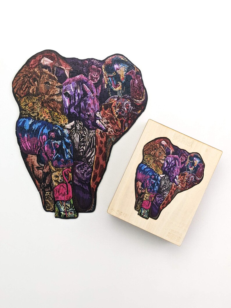 Puede incluir: Un rompecabezas de madera en forma de cabeza de elefante compuesto por varios animales, incluyendo un le&oacute;n, una cebra, una jirafa y un flamenco. El rompecabezas es colorido y detallado.