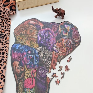 Puede incluir: Un rompecabezas de madera colorido en forma de elefante con varios animales en su interior, incluyendo una cebra, un le&oacute;n, un flamenco y un gato. Faltan algunas piezas del rompecabezas.