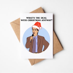 May include: A white card with a blue circle and a cartoon image of a man wearing a red Santa hat and a brown suit holding a microphone. The text on the card reads "What's the deal with Christmas anyway?"