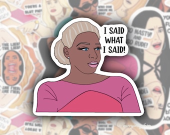 Peut inclure: Un autocollant représentant une femme de dessin animé avec des cheveux blonds et une peau brune. Elle porte une chemise rose et a une expression sérieuse sur son visage. Le texte "I said what I said!" est écrit en lettres blanches sur un fond blanc.