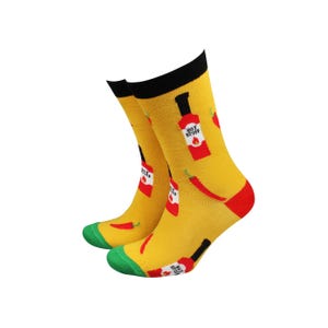 May include: A pair of yellow socks with black cuffs, red heels and toes. The socks feature a pattern of red chilli peppers and red hot sauce bottles with the text "HOT STUFF".