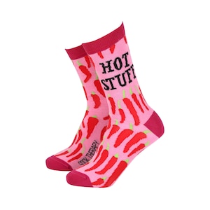 May include: A pair of pink socks patterned with red chili peppers and the words "HOT STUFF" in black. The socks have a dark pink cuff, heel, and toe. The text "SOCK THERAPY" is printed on the side of the socks.