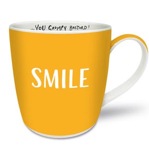 Puede incluir: Una taza de cerámica amarilla con interior y asa blancos. La palabra "SMILE" está impresa en letras blancas en la parte delantera. Encima del borde, el texto dice "...YOU GRUMPY BASTARD!"
