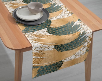 May include: A gold and teal table runner with a geometric pattern. The runner is on a wooden table with a bowl and plate on top.