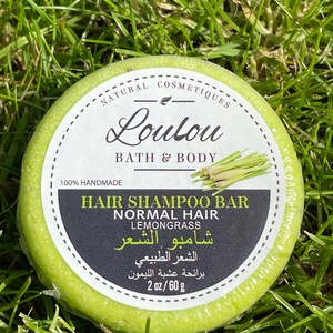 以下が含まれることがあります： ラベルに「NATURAL COSMETIQUES Loulou BATH & BODY 100% HANDMADE HAIR SHAMPOO BAR NORMAL HAIR LEMONGRASS شامبو الشعر الشعر الطبيعي برائحة عشبة الليمون 2 oz/60 g」と書かれた緑色のヘアシャンプーバー。