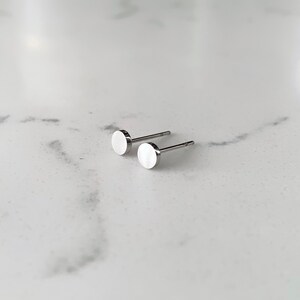 May include: A pair of silver stud earrings with round, flat fronts.