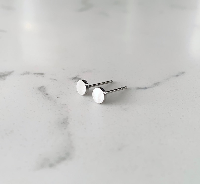 May include: A pair of silver stud earrings with round, flat fronts.