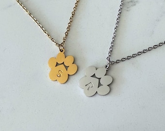 Pode incluir: Dois colares de ouro e prata com pingentes de pata. O pingente de ouro tem a letra "S" no centro e o pingente de prata tem a letra "R" no centro.