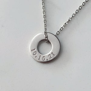 May include: A silver necklace with a round pendant that has the date 10.16.21 engraved on it.