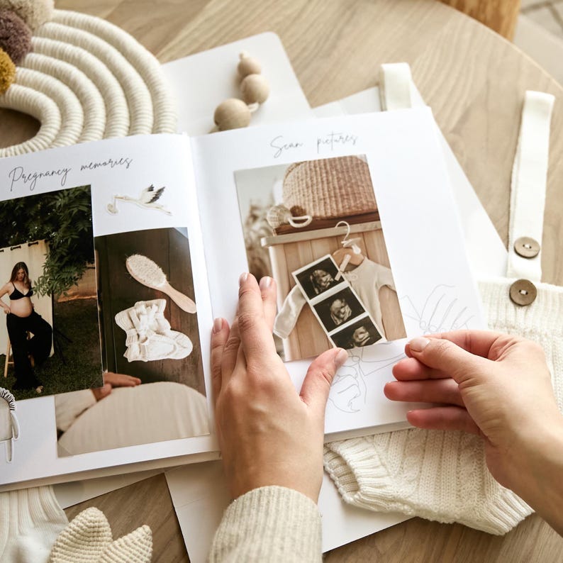 May include: A photo album open to pages with the words "Pregnancy memories" and "Scan pictures." The album contains photos of a pregnant person, baby clothes, and ultrasound images. The album is on a light-colored wooden surface.