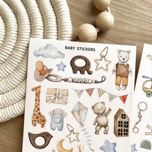 May include: A sheet of baby stickers with watercolor illustrations. Designs include a pacifier, elephant, giraffe, teddy bear, and a kite. The stickers are in soft pastel colors, with the words "BABY STICKERS" at the top.