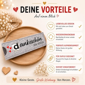 May include: A grey felt sleeve with a cutout window displaying the letter d, featuring the text dankesch&ouml;n VON HERZEN and red heart icons. The sleeve is presented on a round wooden tray alongside a list of five benefits with icons.