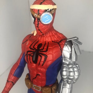 May include: A red, blue, and black Spider-Man action figure with a steampunk-inspired design. The figure features a metallic arm, goggles, and stitched details. The figure has a black spider emblem on the chest and a brown utility belt.