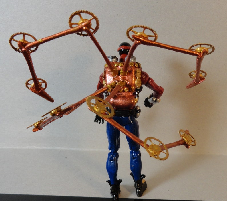May include: A steampunk-themed action figure with a red and copper-colored torso, blue pants, and black boots. The figure has multiple articulated copper arms with gold-colored gears attached. The figure is posed against a plain background.