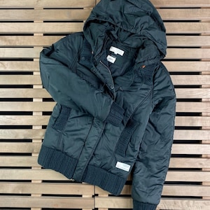 May include: A dark green hooded puffer jacket with a knitted trim around the hood, cuffs, and hem. The jacket has a zip closure and a button closure.