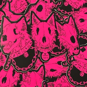 Pode incluir: Um monte de adesivos rosa e preto com um cão de três cabeças com crânios e um colar de corrente. O texto no adesivo diz "Cerberus".