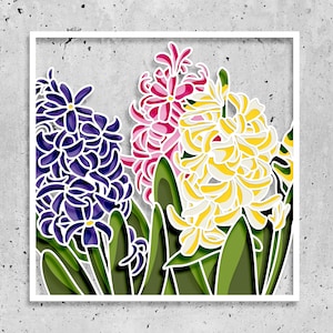 Puede incluir: Un marco blanco con un diseño de papel recortado de tres jacintos en morado, rosa y amarillo.