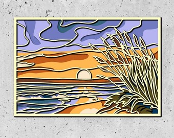 May include: A paper cut-out art piece depicting a sunset over a beach with tall grass in the foreground. The sky is a gradient of purple, blue, and orange. The sun is a bright yellow circle. The water is a deep blue with white waves. The grass is a light green with brown stalks.