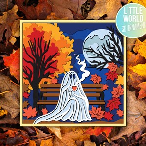 Pu&ograve; includere: Un ornamento di carta 3D che rappresenta un fantasma seduto su una panchina in un ambiente boschivo autunnale. Il fantasma indossa un lenzuolo bianco e tiene una tazza di caff&egrave;. Il bosco &egrave; pieno di foglie colorate e una luna piena pende nel cielo.