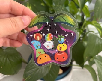 May include: A clear sticker with a star-shaped design featuring cartoon characters and gifts. The sticker has a dark purple and blue background with white stars. The characters are in various colors, including blue, orange, and yellow.