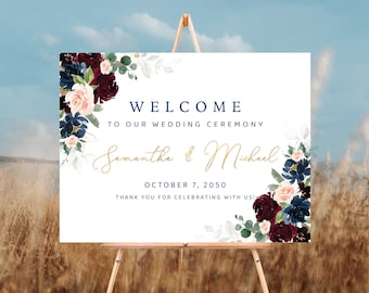 May include: A white wedding welcome sign with a floral design in shades of burgundy, pink, blue, and green. The sign reads "Welcome to our wedding ceremony Samantha & Michael October 7, 2050 Thank you for celebrating with us!"