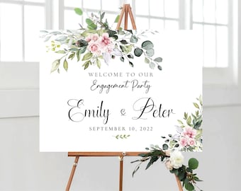 Könnte beinhalten: Ein weißes Willkommens-Schild mit grünen und rosafarbenen floralen Akzenten. Das Schild lautet "Willkommen zu unserer Verlobungsfeier Emily & Peter 10. September 2022".