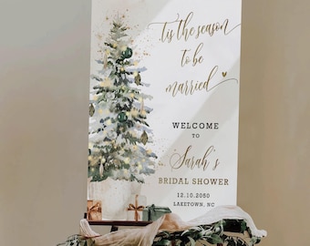 May include: A welcome sign for a bridal shower. The sign features a watercolor Christmas tree with gold accents and the text "Tis the season to be married." It welcomes guests to Sarah's bridal shower on 12.10.2050 in Laketown, NC.