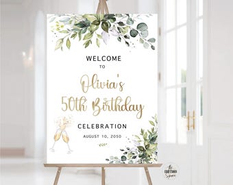 May include: Welcome to Olivia's 50th Birthday Celebration, 10 August 2050. A white sign with gold lettering and green watercolour floral design.