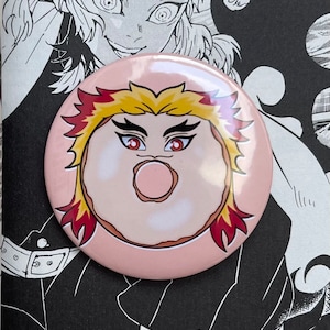 Puede incluir: Un botón rosa con una imagen de dibujos animados de una dona con llamas rojas y amarillas. La dona tiene un glaseado blanco y un centro rosa.