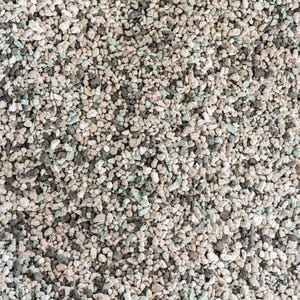 May include: Close-up of a textured surface composed of small, irregularly shaped pebbles. The pebbles are primarily shades of gray, white, and a hint of pale green, creating a natural, earthy appearance. The arrangement is dense and uniform.
