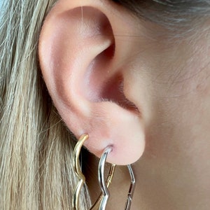 Peut inclure: Une paire de boucles d'oreilles cr&eacute;oles en forme de c&oelig;ur. Une boucle d'oreille est dor&eacute;e et l'autre est argent&eacute;e.