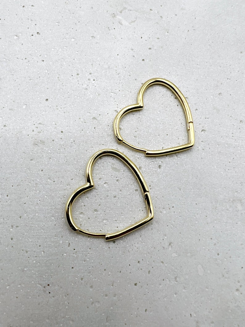 Peut inclure: Une paire de boucles d'oreilles cr&eacute;oles en forme de c&oelig;ur dor&eacute;es. Les boucles d'oreilles sont simples et &eacute;l&eacute;gantes, et seraient un excellent cadeau pour toute occasion.