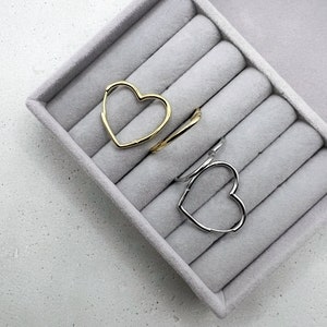 Peut inclure: Deux boucles d'oreilles cr&eacute;oles en forme de c&oelig;ur, l'une dor&eacute;e et l'autre argent&eacute;e, pr&eacute;sent&eacute;es dans un &eacute;crin &agrave; anneaux en velours gris.