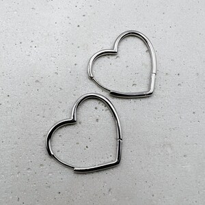 Peut inclure: Deux boucles d'oreilles cr&eacute;oles en forme de c&oelig;ur argent&eacute;es. Les boucles d'oreilles sont simples et &eacute;l&eacute;gantes.