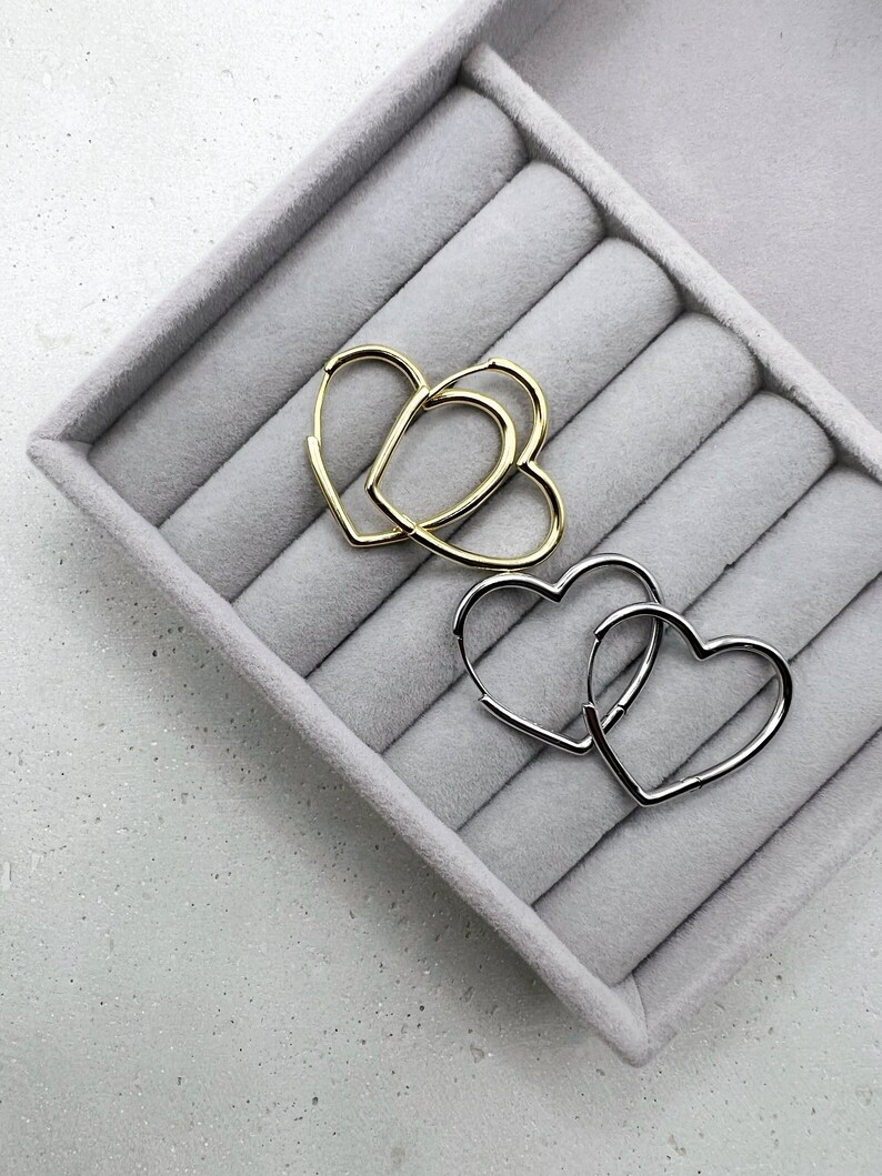 Peut inclure: Deux paires de boucles d'oreilles cr&eacute;oles en forme de c&oelig;ur, une paire en or et une paire en argent, pr&eacute;sent&eacute;es dans un &eacute;crin &agrave; anneaux en velours gris.