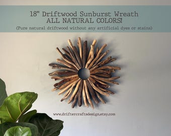 May include: An 18-inch sunburst wreath constructed from natural driftwood pieces in varying shades of brown and tan, arranged in a circular pattern around a central opening. The text reads 18" Driftwood Sunburst Wreath ALL NATURAL COLORS!