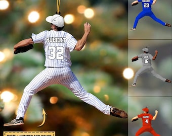 May include: A baseball player ornament with a white and black striped jersey, a white cap, and the name "ROBERT" and number "32" on the back. The ornament is in a pitching pose. The text "NAME & NUMBER AND COLOR CAN BE CUSTOMIZED" is at the bottom of the image.