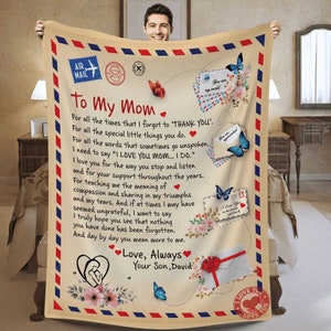May include: A beige and brown blanket with a vintage letter design. The blanket features a message to "Mom" with a heartfelt message about love, support, and appreciation. The blanket includes illustrations of butterflies, flowers, and envelopes.