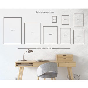 May include: A white wall with a desk and chair in front of it. The wall has a grid of different sized frames with the text "Print size options" and the dimensions of each frame in inches. The text "Desk size is 60 in" is below the frames.