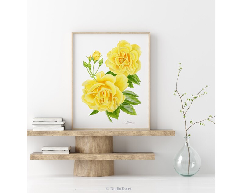 May include: A watercolor painting of two yellow roses with green leaves and buds. The painting is framed and displayed on a white wall.