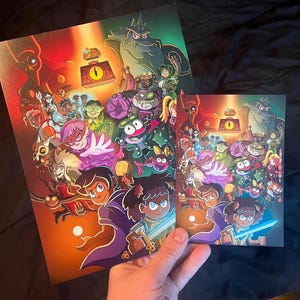 Pode incluir: Duas impress&otilde;es de uma ilustra&ccedil;&atilde;o colorida com um grupo de personagens de desenhos animados, incluindo uma menina com cabelo castanho e uma capa roxa, uma criatura verde semelhante a um sapo e um monstro grande, cinza e peludo. A ilustra&ccedil;&atilde;o est&aacute; sobre um fundo escuro com um orbe brilhante no centro.