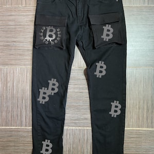 Könnte beinhalten: Schwarze Jeans aus Denim mit großen Cargo-Taschen, die mit einem Bitcoin-Logo verziert sind. Die Jeans haben eine schmale Passform und einen Reißverschluss.